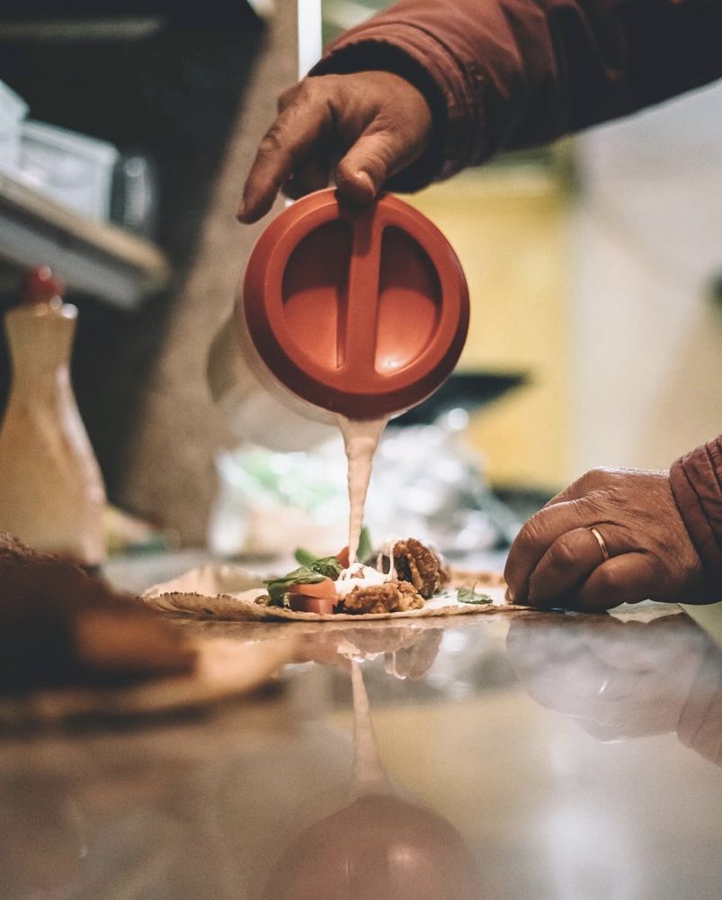 Finishing a falafel wrap with tarator sauce at Raffoul Takeaway
